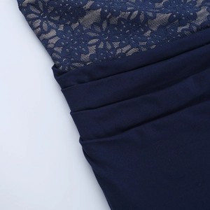 Detail of dark blue lace evening gown showing floral embroidery and pleated fabric texture