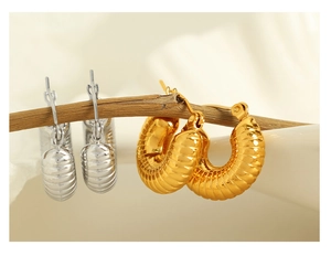 Artistic close-up of gold and silver hollow hoop earrings on a dry tree branch