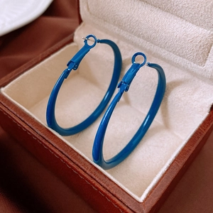 Close-up of vibrant blue enamel hoop earrings displayed in a luxury beige jewelry box
