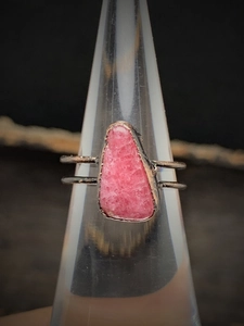 Macro shot of vintage irregular pink natural stone ring on a clear jewelry stand