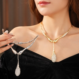 Détail de pendentifs gouttes d'eau dorés et argentés avec strass brillants portés par le mannequin