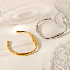 Artistic wave-shaped irregular bangles in gold and silver finish with soft lighting