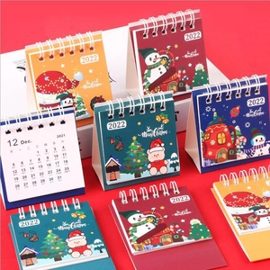 Close-up of 2022 mini Christmas desk calendars with festive cartoon covers and wire binding