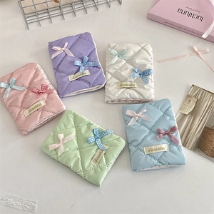 Quilted passport covers in various colors with bow decorations and elegant metal tags