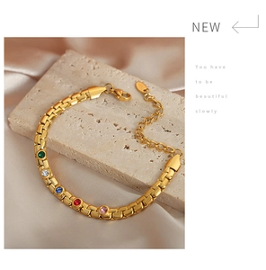Detail view of a gold plated bracelet with five colorful stones on a silk background