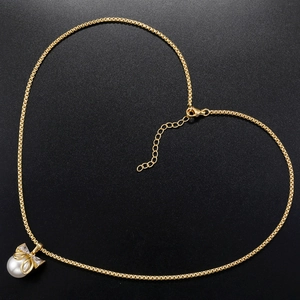 Elegant gold bow necklace with pearl pendant arranged in heart shape on dark background