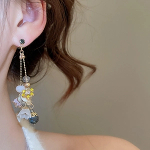 Detail view of long crystal flower earrings on model with golden chain and drop pendant