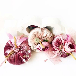 Close-up of handmade velvet pumpkins with pearls, ribbons and floral accents for home decor
