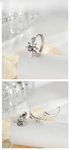 Macro detail of starburst and bow-shaped silver earrings with grey zircon stones