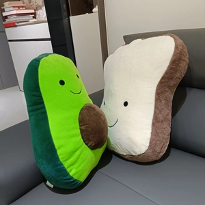 Close-up of cute plush avocado and toast pillows with smiling faces on a sofa