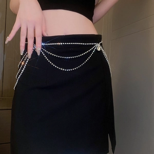 Detail of silver rhinestone layered body chain with water drop pendants on black dress