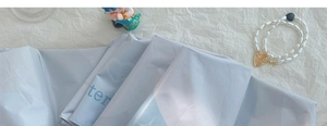 Detail of light blue sun umbrella packaging bag with heart pattern and pearly beads
