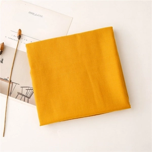 Detalle de bufanda de algodón y lino amarillo suave con textura tejida en fondo minimalista
