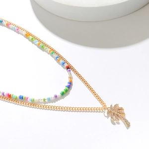 Close-up of rainbow beaded necklace with golden palm tree pendant and sparkly rhinestones