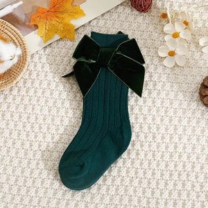 Detail of forest green knit baby socks with large velvet bows and vertical textures