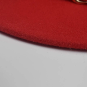 Detailaufnahme von rotem Wollfilz und goldener Schnalle an der Krempe eines Filzhutes