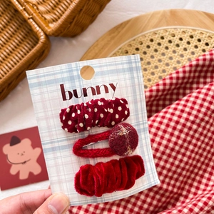 Close-up of three red velvet and knit bow hair clips on a decorative bunny card
