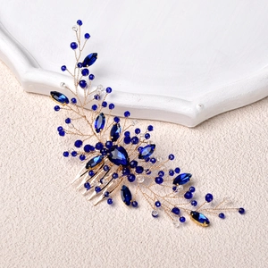 Exquisite bridal hair comb with deep blue crystals and gold wire on a textured background