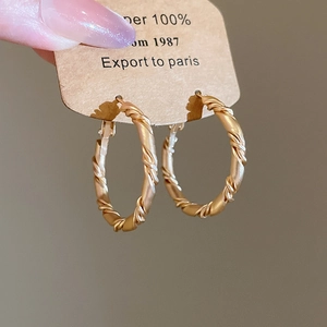 Detail of matte gold twisted rope hoop earrings with a textured spiral vintage design