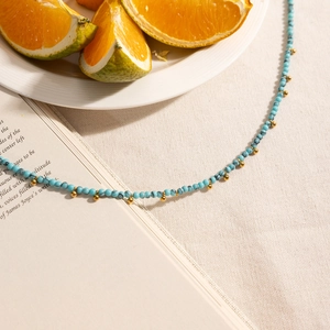 Artistic detail of turquoise bead necklace with gold accents on a book background