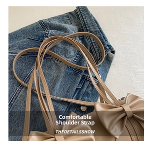 Close-up of beige shoulder bag with double bow details and matte leather texture