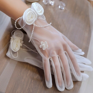 Detailed close-up of white tulle bridal gloves with fabric roses and pearl chains