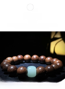 Détail du bracelet en bois de santal avec grain doré et perle vert clair