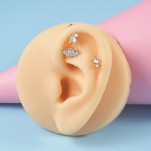 Macro view of silver ear stud with marquise zircon leaves on a silicone model ear
