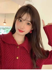 Detailed view of red New Year stud earrings with gold Fu character on a knit cardigan