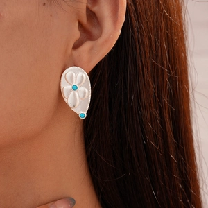 Detail of silver drop earrings with turquoise inlay and engraved floral pattern on model