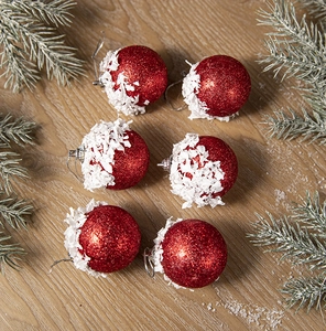 Detail of 6pcs red glitter Christmas ornaments with faux snow on rustic wood background