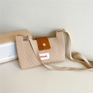 Detail of beige knitted crossbody bag with caramel brown magnetic clasp and diamond texture