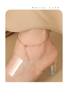 Detail of rose gold LOVE letter anklet worn with clear high heels for a stylish look