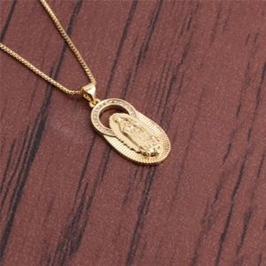 Close-up of gold Virgin Mary pendant with cubic zirconia on wood background