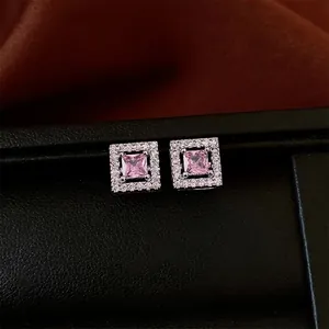 Quadratische rosa Zirkon-Ohrstecker mit Silberbasis und Halo-Design auf schwarzer Box