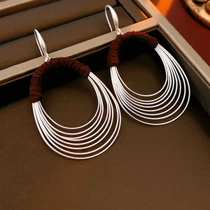 Detailed macro shot of multilayer silver hoop earrings with brown fabric wrap detail