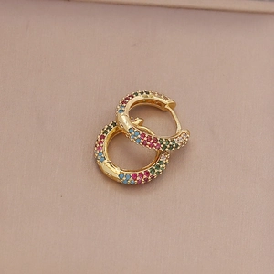 Golden hoop earrings with colorful zircon stones on a soft beige leather surface