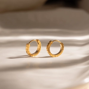 Close-up of 18K gold-plated ribbed hoop earrings with segmented geometric texture
