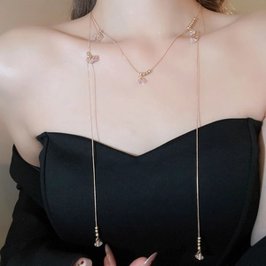Vue détaillée du collier doré multicouche avec pendentifs en zircon sur tenue noire