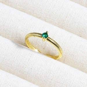 Detail of 18K gold plated ring with green zircon and textured twisted band in a jewelry box