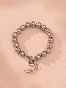 Macro shot of silver stainless steel beaded bracelet with lobster clasp and heart charm