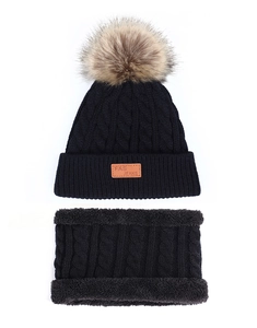 Detail of black knitted beanie and neck warmer set with fuzzy pompom and leather tag
