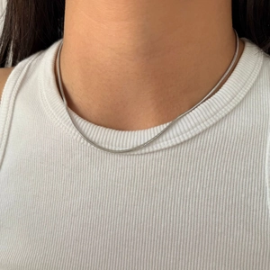 Minimalist silver snake chain necklace shown on a model with white ribbed tank top