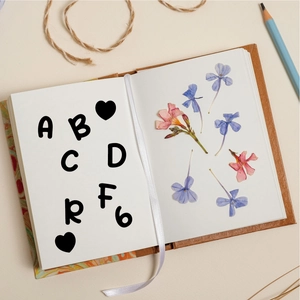 Detailed view of cartoon alphabet stickers on a notebook with dried flowers and twine