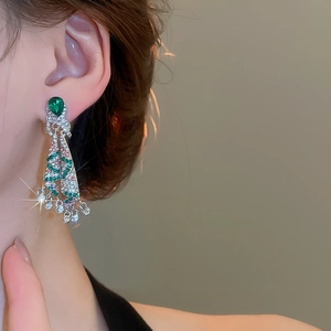 Close-up of Christmas tree drop earrings with colorful crystals on a model's ear