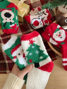 Close-up of coral fleece Christmas socks featuring Santa and elk patterns in festive colors