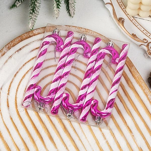 Close-up of pink and white spiral candy cane ornaments with glitter on a snowy tray