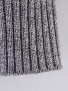 Macro detail of soft grey rib-knit texture on a minimalist short cardigan sweater
