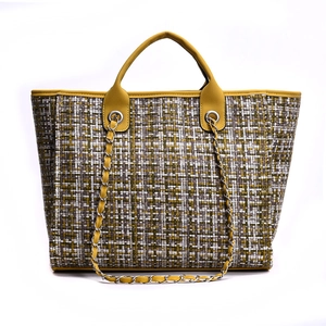 Close-up of yellow tweed tote bag showing textured weaving and leather chain handles
