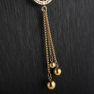 Macro detail of gold long necklace featuring sparkling rhinestones and elegant fringe chains